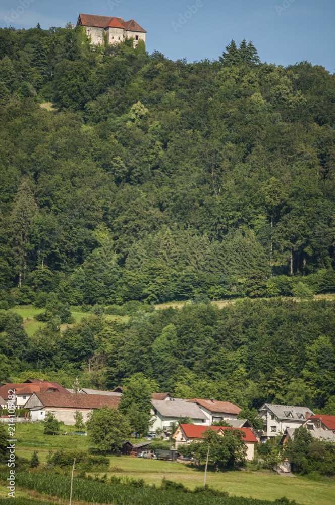 Slovenia: uno dei tipici villaggi sloveni con un castello sulla cima di una collina, i prati verdi, gli alberi e terreni coltivati in campagna