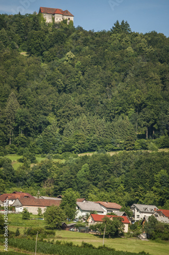 Slovenia: uno dei tipici villaggi sloveni con un castello sulla cima di una collina, i prati verdi, gli alberi e terreni coltivati in campagna