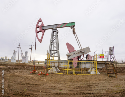 The beam pumping unit is homework, sunset in oil field. Oil pump oil rig energy industrial machine for petroleum. The pumping unit as the pump installed on a well. Equipment of oil fields.