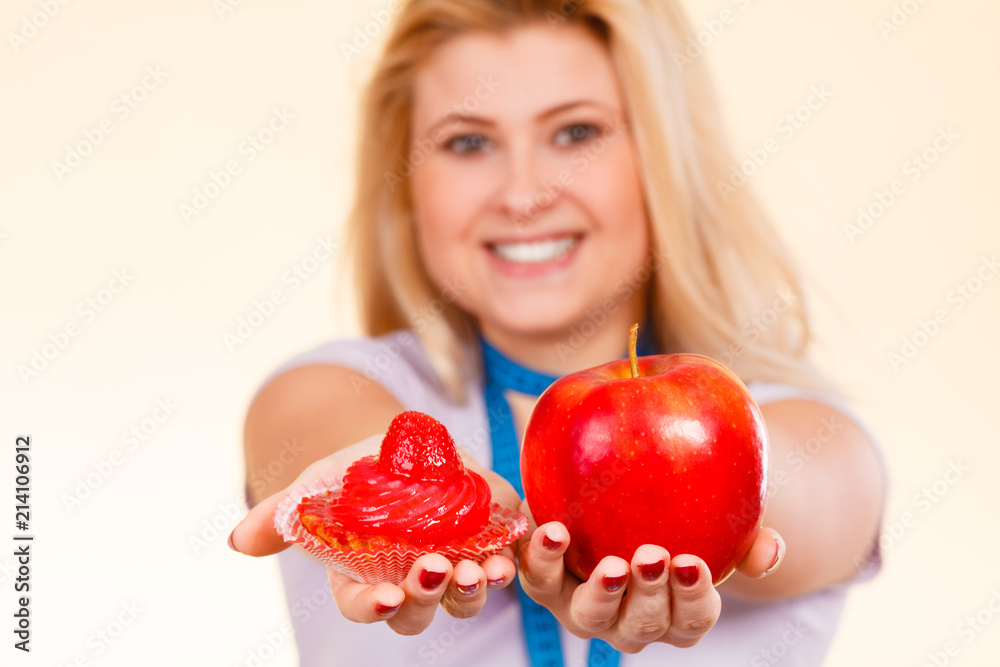 Woman choosing between apple and sweet cupcake Woman choosing between apple and sweet cupcake