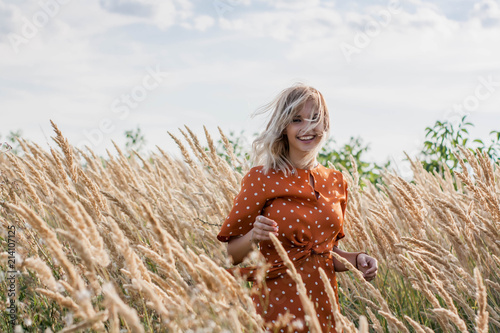 Cheerful beautiful young woman having fun and posing on the field at sunset photo