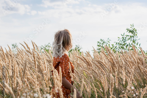 Cheerful beautiful young woman having fun and posing on the field at sunset photo