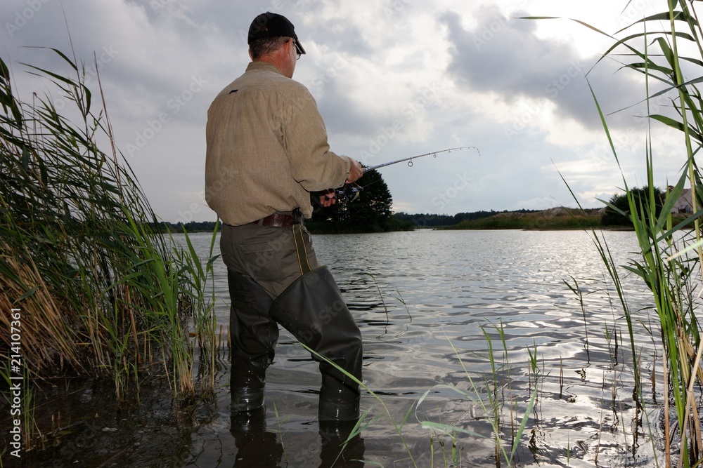 Angler catching the fish during stormy weather Angler catching the fish during stormy weather