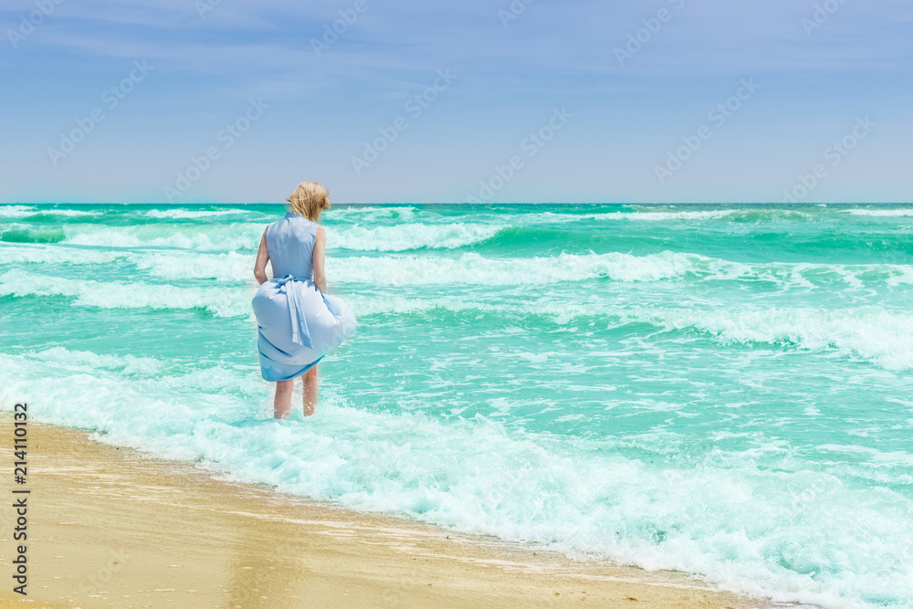 Woman in blue dress in the water in the ocean, the sea.