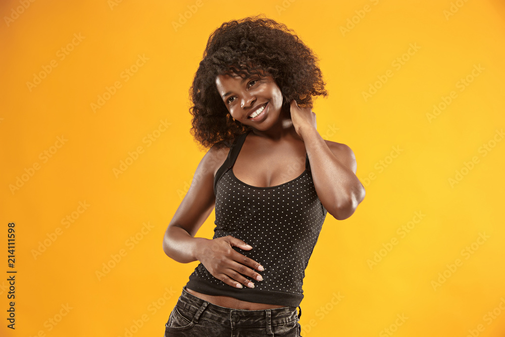 The happy business woman standing and smiling against gold background.