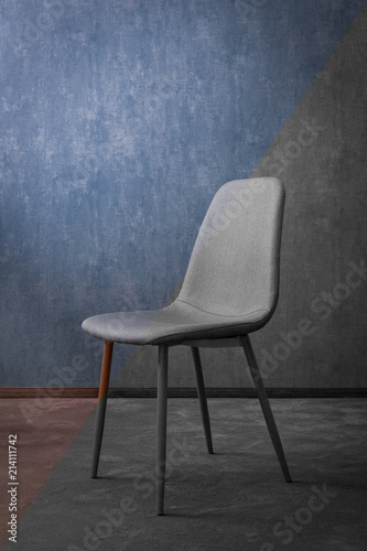 Grey modern textile chair with wood on a background of a wall.