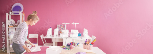 Tailor measuring textile material. young woman seamstress making pattern on fabric with tailors chalk. Girl working with a sewing pattern. Hobby sewing as a small business concept.