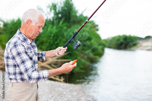 Mature man angling at riverside
