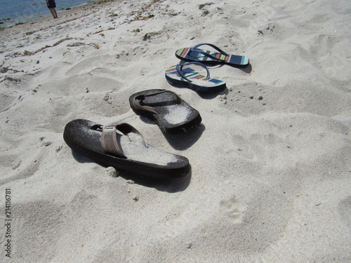 A man and a woman's pair of flip flops in the sand on the beach 