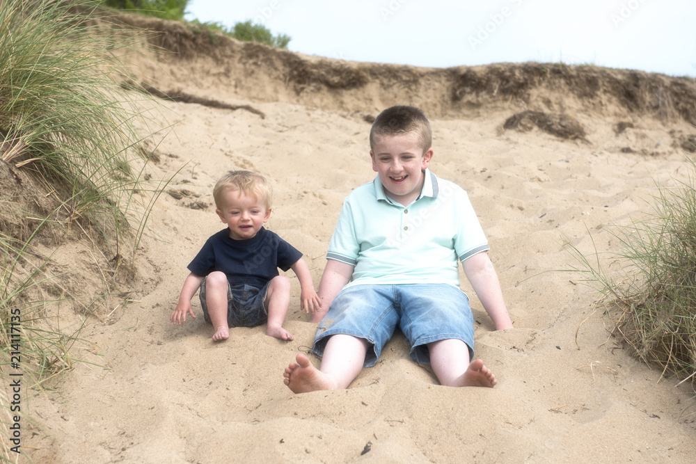 Two brothers playing in the sand on the beach Two brothers playing in the sand on the beach
