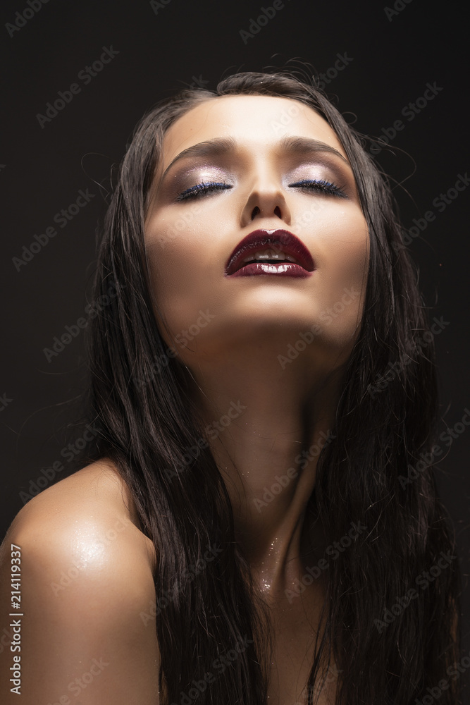 Beautiful sensual young brunette girl model with naked shoulders and dark red lips makeup on dark background. Beautiful sensual young brunette girl model with naked shoulders and dark red lips makeup on dark background.