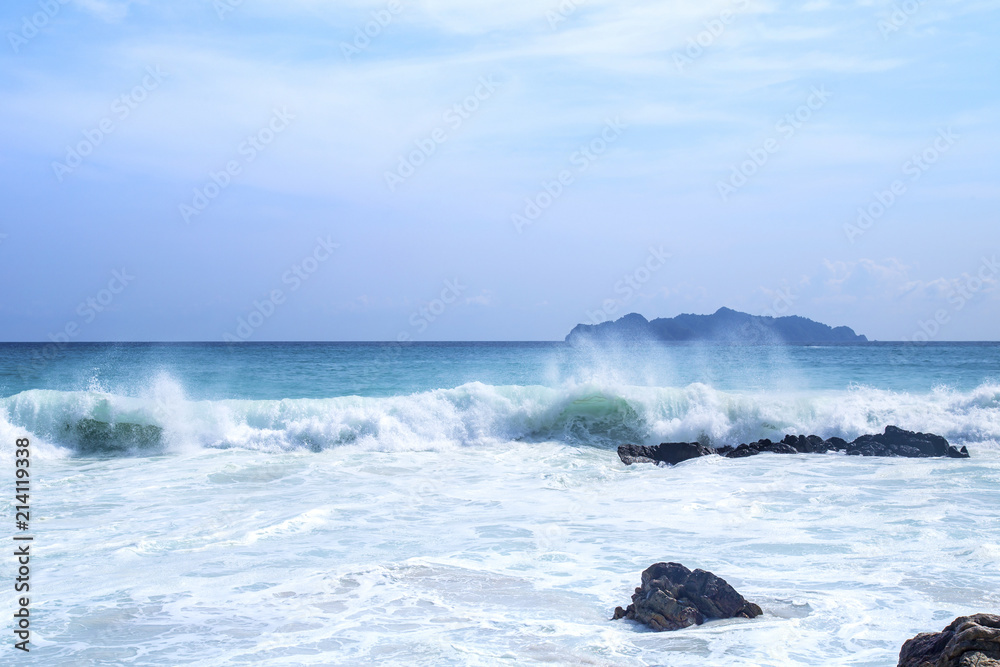 Splashing waves on the rocks and blue sky