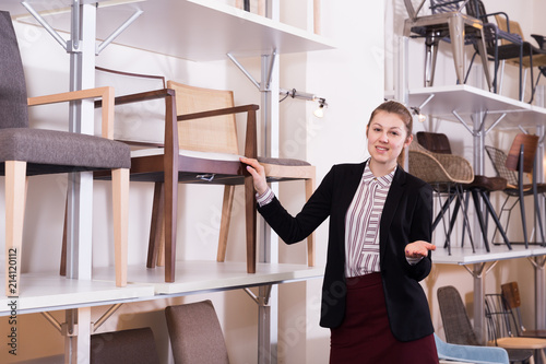 Saleswoman suggesting armchair in furniture salon photo