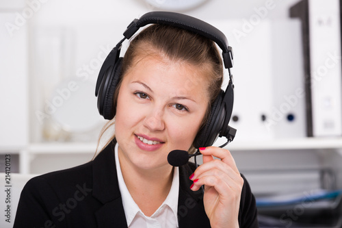 Portrait of office worker woman in black suit which is talking by headset with client