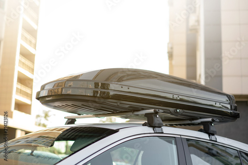 long black trunk on the roof of a white car. Travel and accessories for transportation. photo