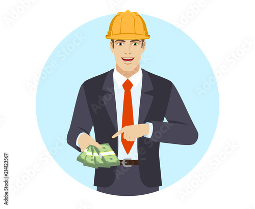 Businessman in construction helmet pointing at money in his hand