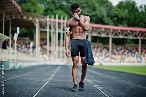 African american male athlete sexy sport bare torso man with running sports arm case for mobile phone, posed at stadium.