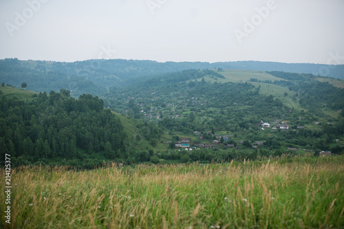 A picturesque panoramic landscape of the picturesque green mountain valley in spring. Historical village with flowering trees and traditional houses. Colorful travel background