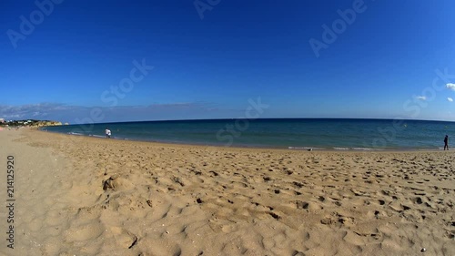 ALVOR, PORTUGAL, 12.06.2018: Sunny day at a beach, couple man and a woman walking by waterline, fitness girl running at the beach