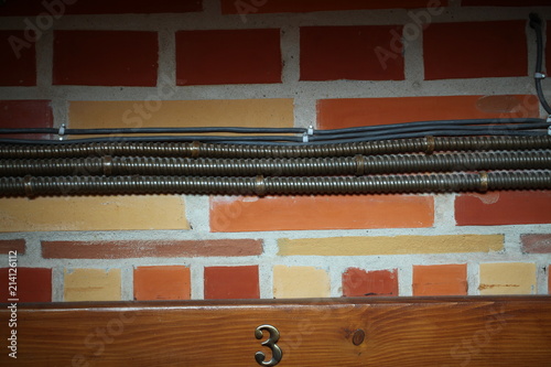 electrical wiring in a metal casing on the wall of a brick building inside