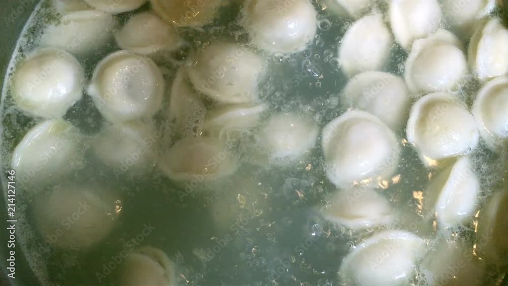Process of cooking homemade dumplings. Meat dumplings in boiling water in a pan. Dumplings is traditional russian food. Food background. Close-up. Process of cooking homemade dumplings. Meat dumplings in boiling water in a pan. Dumplings is traditional russian food. Food background. Close-up.