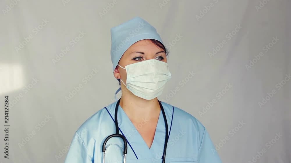 A female doctor with a face mask on his face looks away. The camera moves from right to left A female doctor with a face mask on his face looks away. The camera moves from right to left