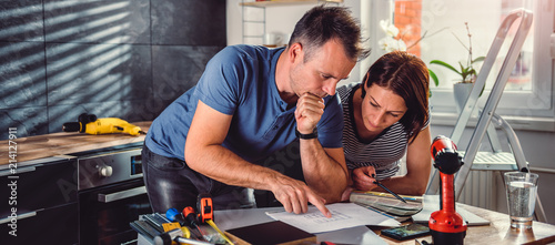 Couple looking at blueprints during kitchen renovation photo