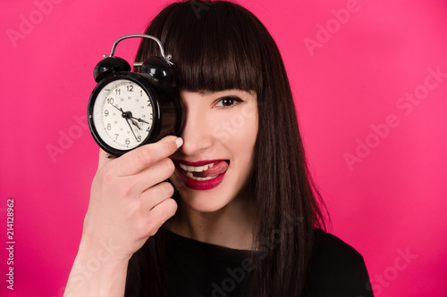 Closeup portrait of stress business woman, student running late with clock hand on head. Concept photo of young employee anxious as project deadline finals approaching isolated pink background