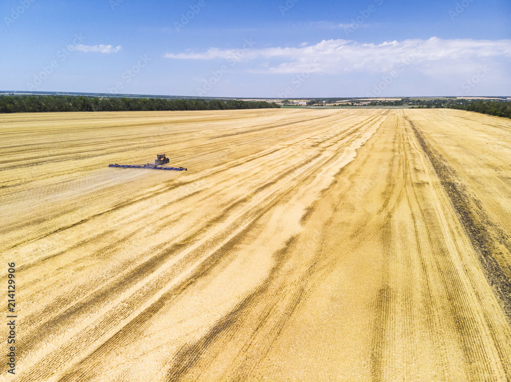 The tractor plows the field after harvesting wheat. Aerial view. The tractor plows the field after harvesting wheat. Aerial view.