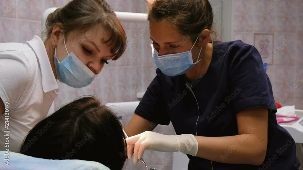 Dentist doctor explains to a young assistant the treatment of teeth, slow motion. Client at the reception at the dentist Dentist doctor explains to a young assistant the treatment of teeth, slow motion. Client at the reception at the dentist