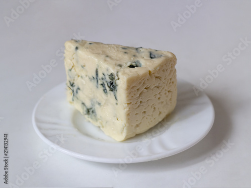 Gorgonzola cheese with blue mold on white plate on light background