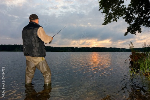 Angler catching the fish during cloudy sunrise