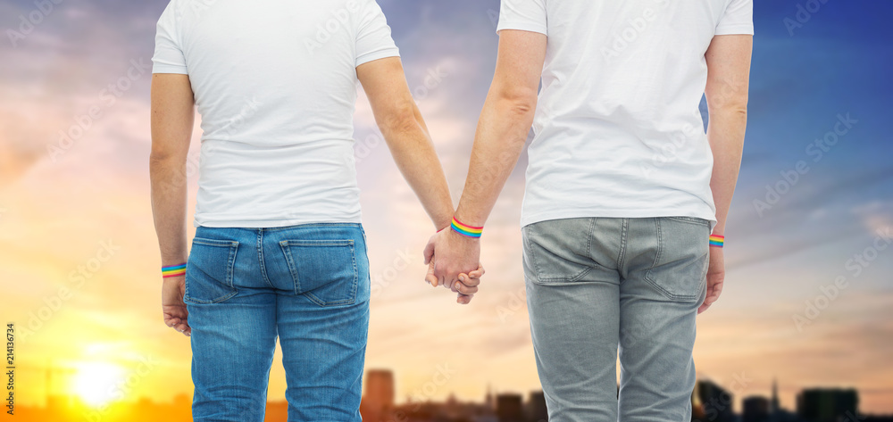 lgbt, same-sex relationships and homosexual concept - close up of male couple wearing gay pride rainbow awareness wristbands holding hands over sunset in tallinn city background lgbt, same-sex relationships and homosexual concept - close up of male couple wearing gay pride rainbow awareness wristbands holding hands over sunset in tallinn city background