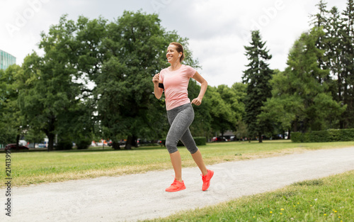 fitness, sport and healthy lifestyle concept - smiling woman with earphones running at park and listening to music © Syda Productions