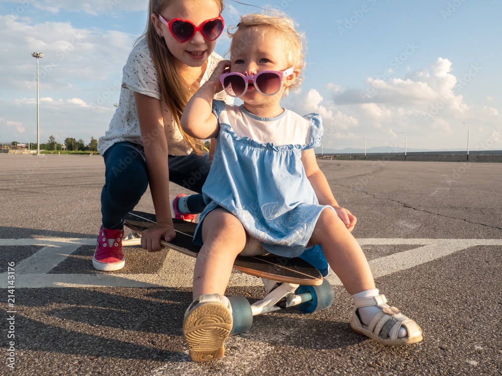 Φωτογραφία Street sports: two dvoichki in sunglasses sit on one large longboard in bright sunny weather