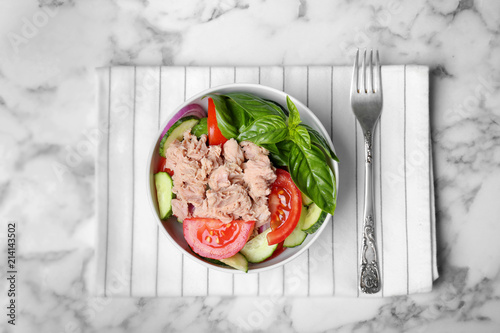 Delicious salad with canned tuna in bowl on marble background, top view photo
