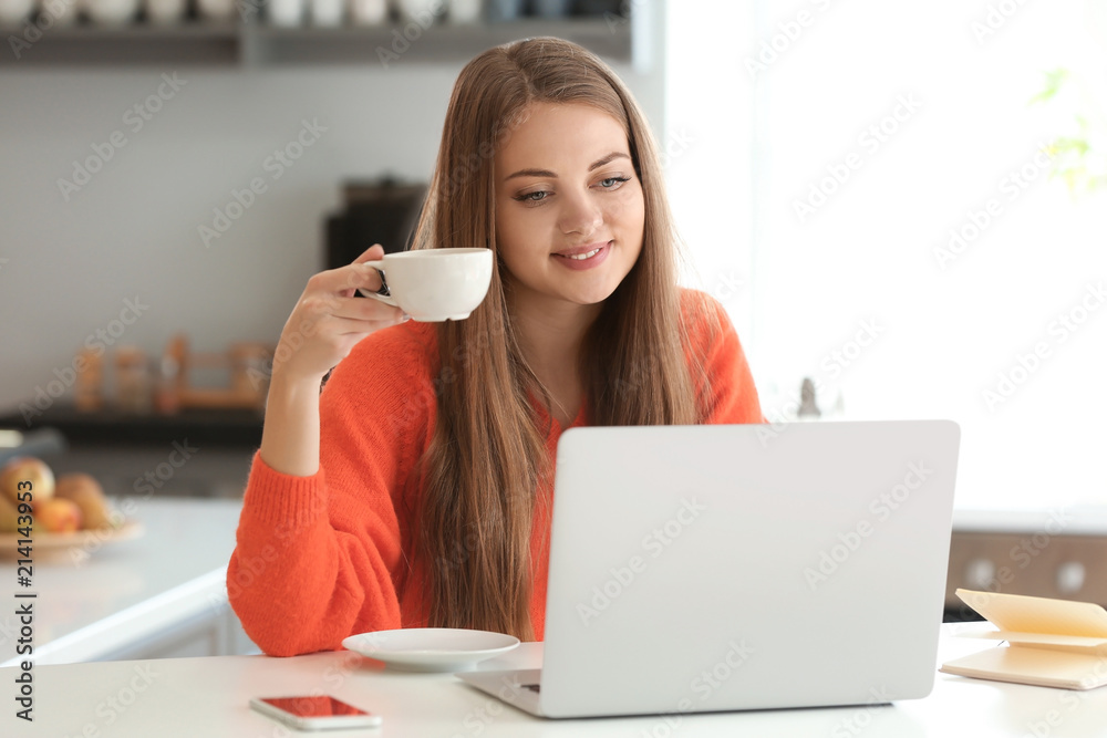 Female freelancer drinking coffee while working on laptop at home Female freelancer drinking coffee while working on laptop at home