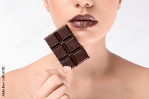 Beautiful young woman with chocolate on white background, closeup photo