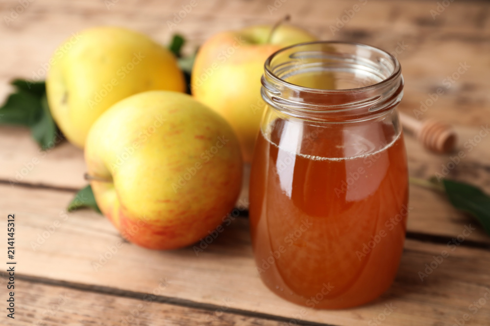 Jar of honey and apples on wooden table Jar of honey and apples on wooden table