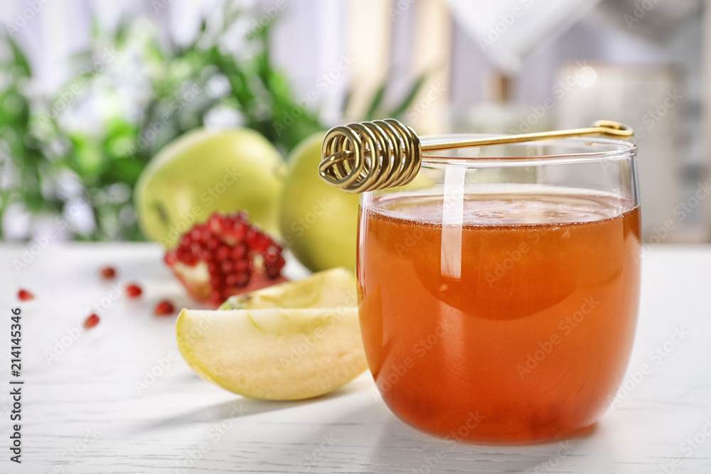 Glass of honey, apples, pomegranate and dipper on light table. Rosh Hashanah holiday Glass of honey, apples, pomegranate and dipper on light table. Rosh Hashanah holiday