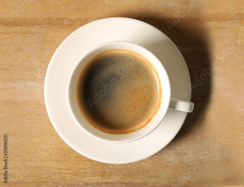 Cup of delicious hot coffee on wooden background, top view