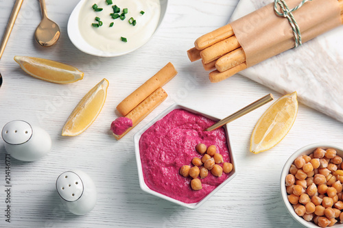 Flat lay composition with bowl of tasty beet hummus, bread sticks and chickpea on light table
