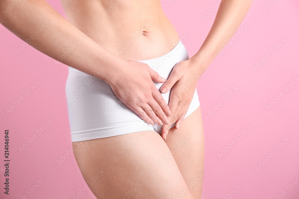 Young woman holding hands near underwear on color background. Gynecology