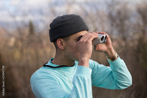 man in aqua coloured shirt looking through binoculars