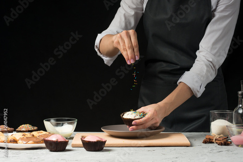 Chef prepares chocolate muffins on a dark background
