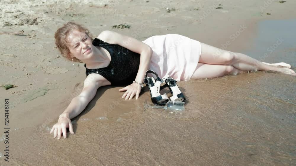drunk woman lies on the beach with a glass of wine after a party
