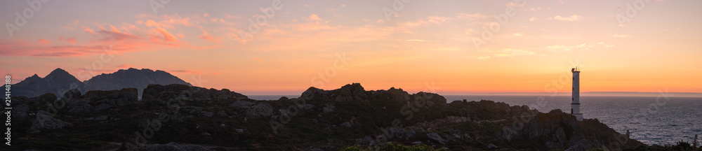Panoramic view of rocky coast with a lighthouse at sunset