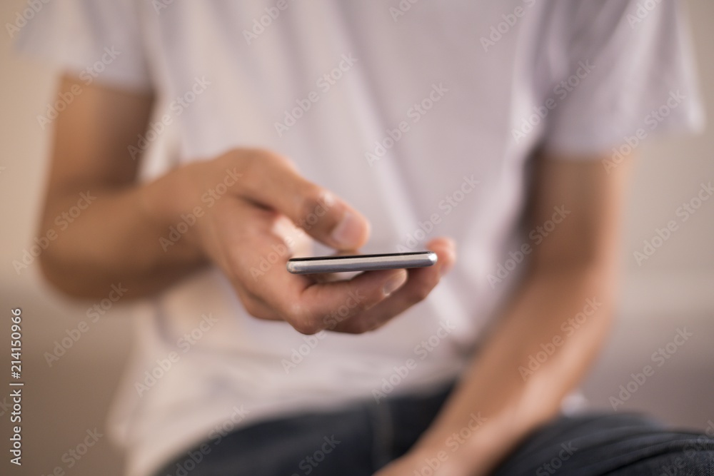 Young man using apps on a touchscreen smartphone - Hands close-up, focus on phone - Jeans and t-shirt - Concept for using technology, shopping online, using mobile apps, texting, phone addiction