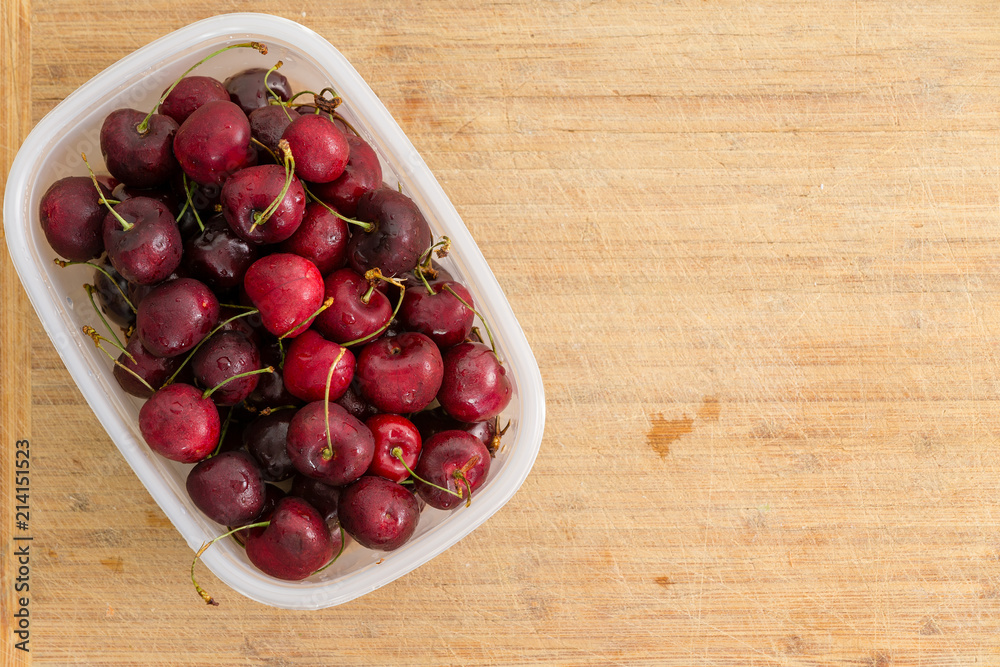 Small plastic container filled with red cherries Small plastic container filled with red cherries
