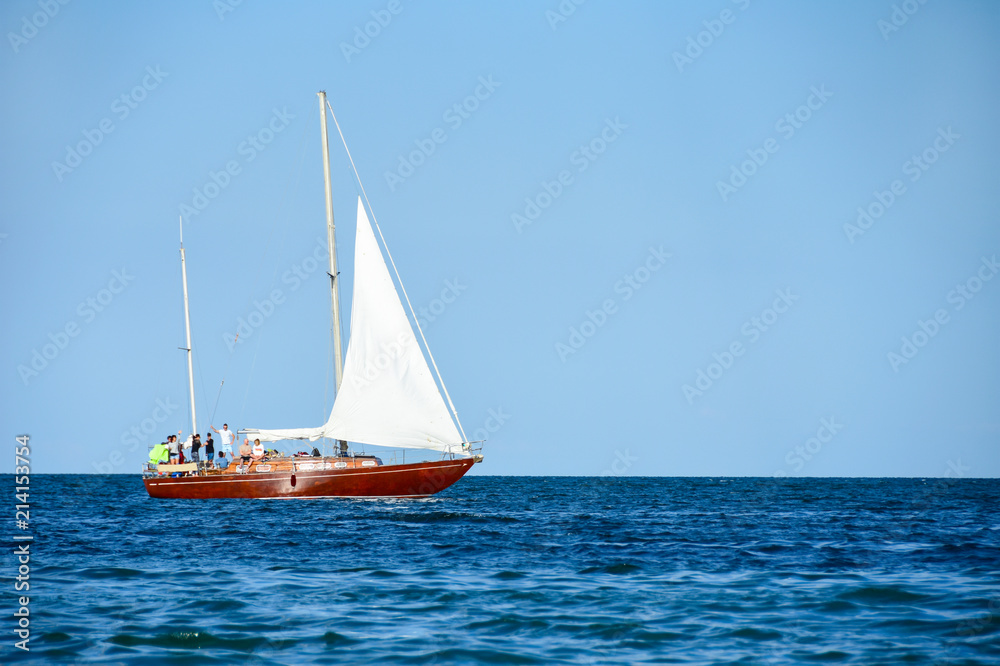 A yacht with tourists sails on the blue sea